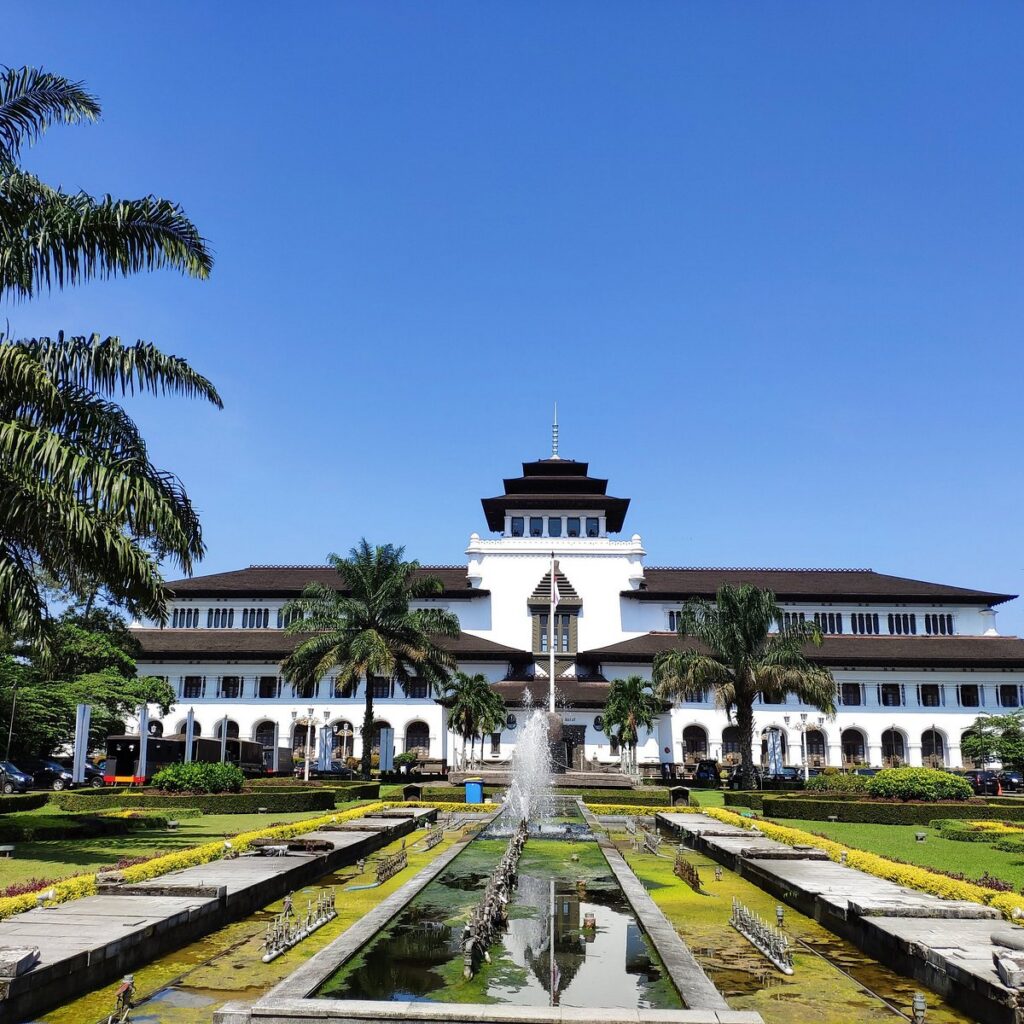 Gedung Sate's white facade and tiered central tower behind formal gardens and a fountain