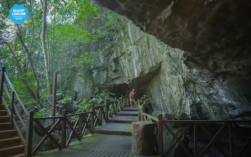 Wooden boardwalk running along a limestone cliff face into the Wind Cave entrance