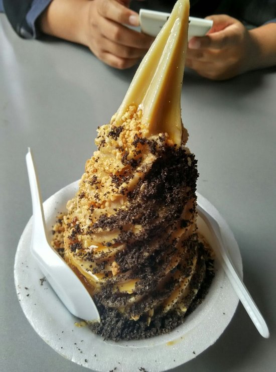 Tall gula apong soft-serve cone coated in peanut crumble and crushed biscuit
