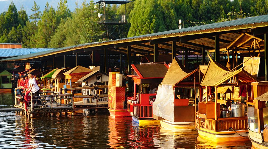 Wooden boat stalls with thatched roofs moored along the lake at Floating Market Lembang
