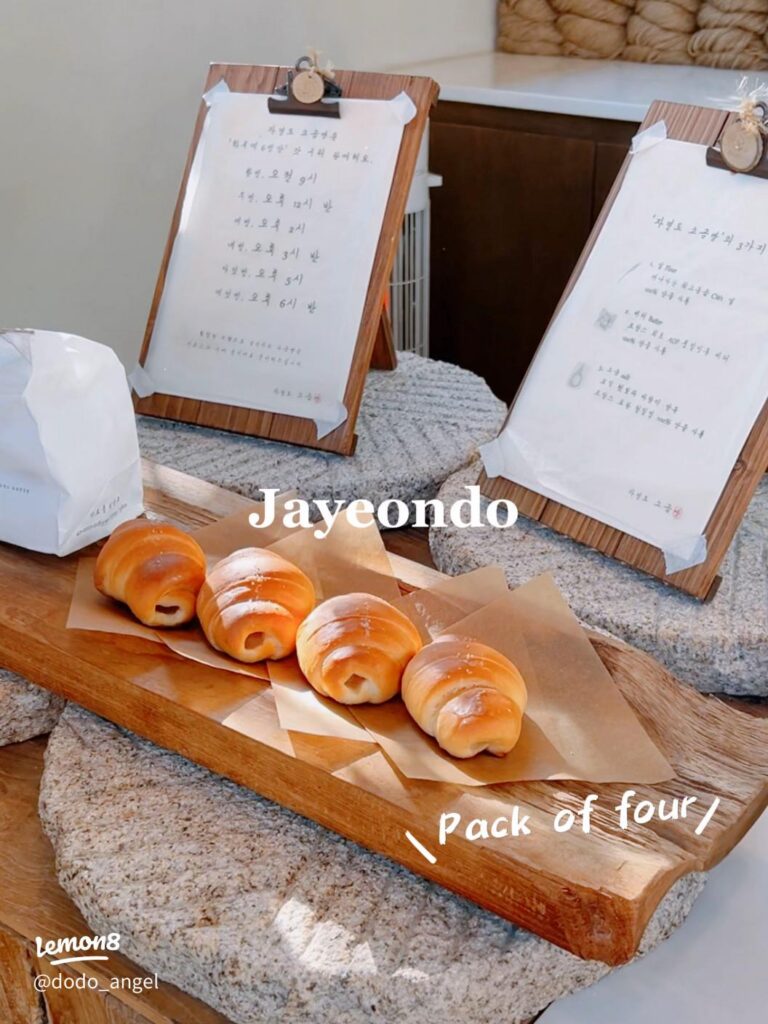 Four glazed salt bread rolls on baking paper on a wooden board, menu cards behind
