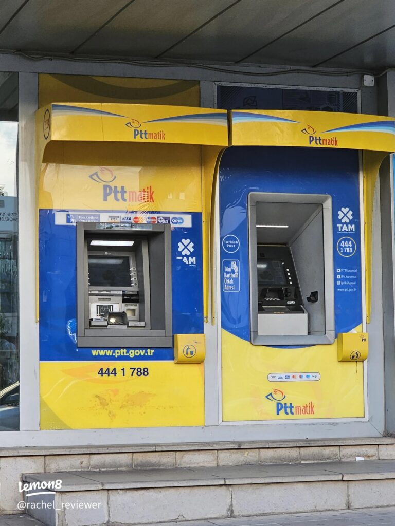 Two yellow-and-blue PTT Pttmatik ATMs at a Turkish post office kiosk