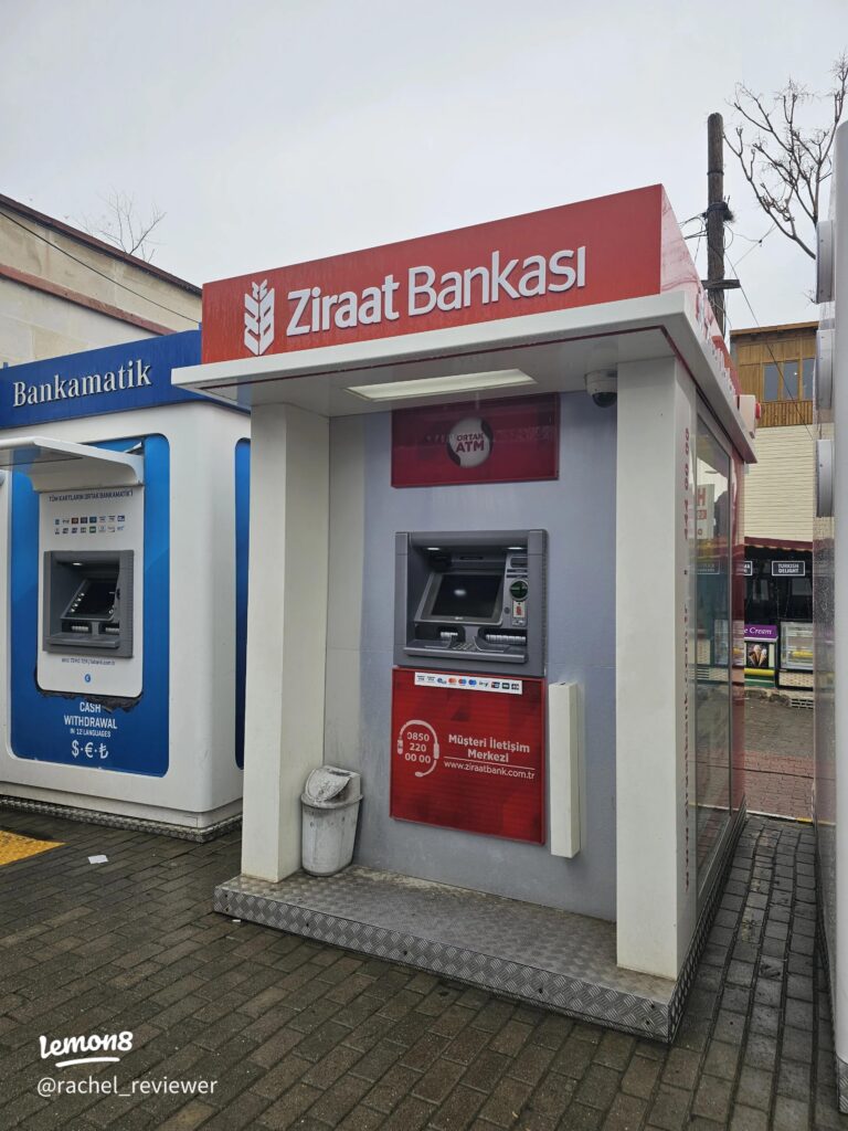 A red Ziraat Bankasi ATM booth beside a blue Bankamatik cash machine