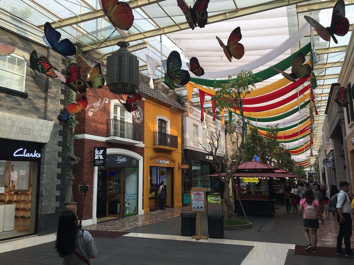 Open-air mall lane hung with large butterfly decorations and coloured bunting
