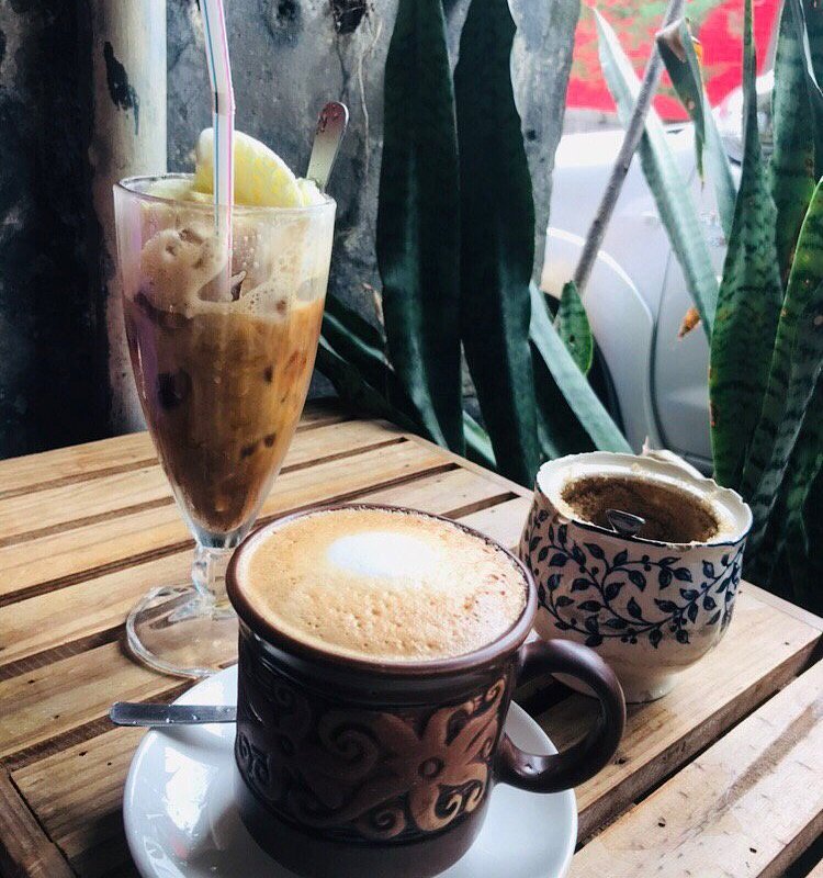 Frothy coffee in a patterned mug beside a tall iced coffee float with ice cream