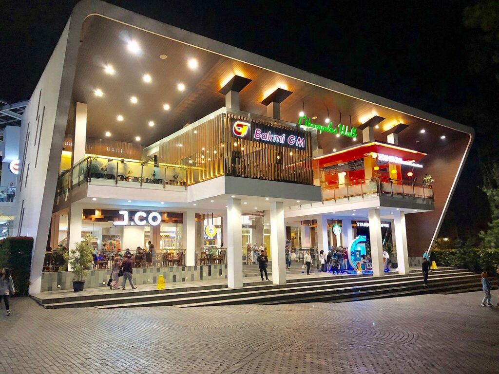 Lit entrance and shopfronts of Cihampelas Walk mall at night