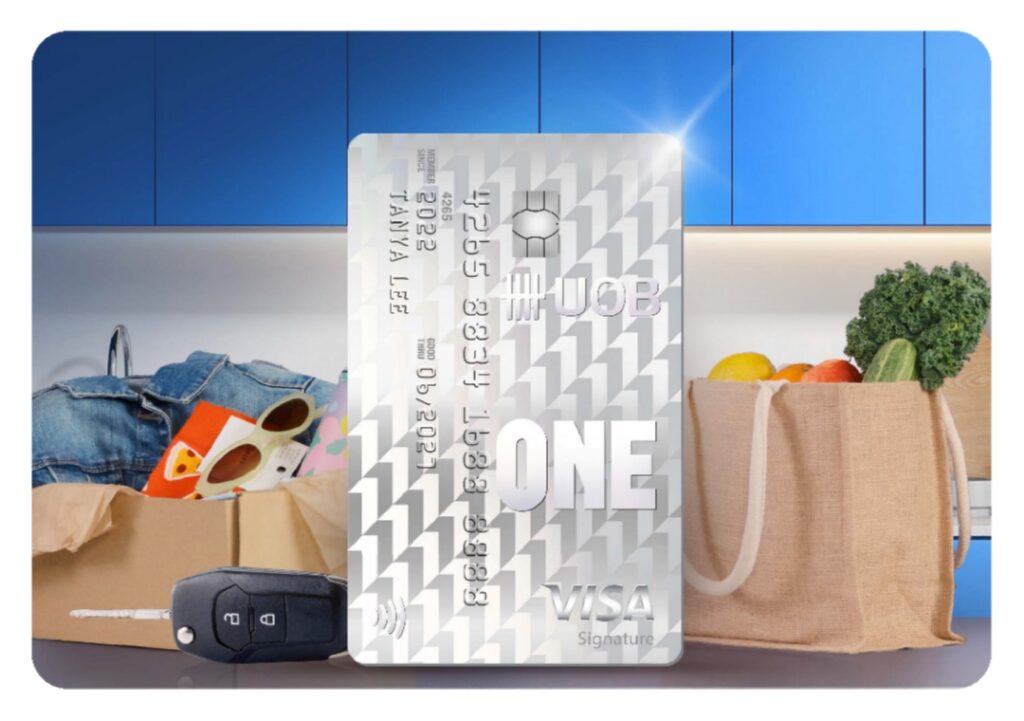 UOB One Visa Signature card standing among grocery bags, clothing and car keys