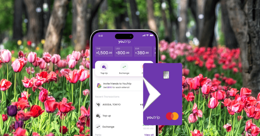 YouTrip app showing multi-currency balances beside the purple YouTrip Mastercard, tulips behind