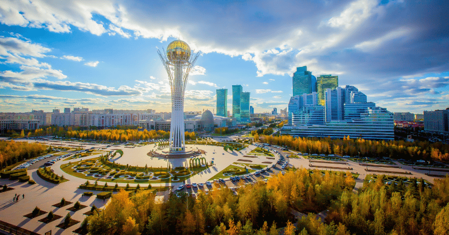 Bayterek Tower's golden sphere rising above Astana's skyline and autumn trees