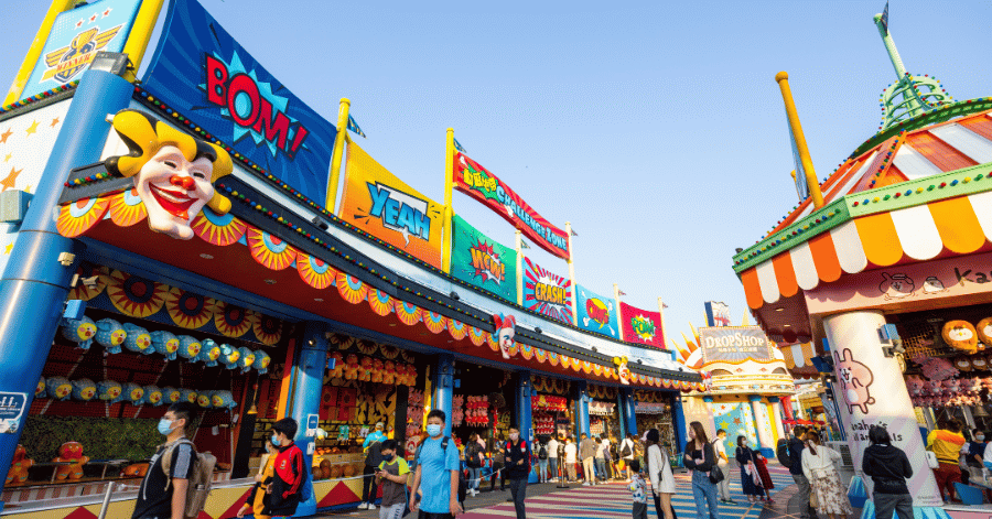Colourful carnival game stalls with a clown face and comic-style signs at Thrill Mountain