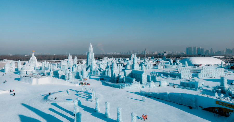 Daytime aerial view of ice towers and sculptures with Harbin's skyline in the distance