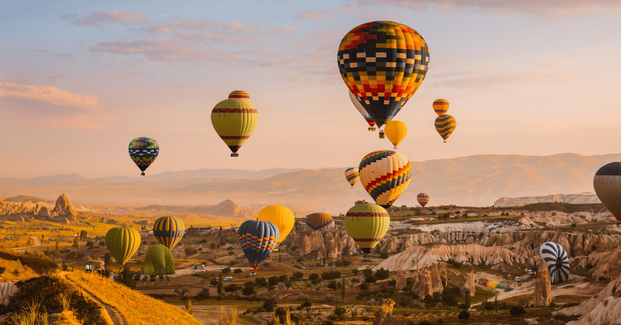 Colourful hot air balloons rising over Cappadocia's rock valleys at sunrise