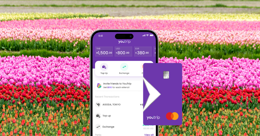 The YouTrip app showing multi-currency balances beside a purple YouTrip card, over a tulip field