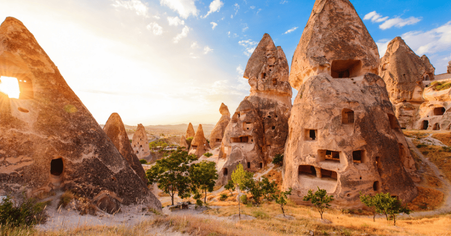 Cone-shaped rock houses and fairy chimneys carved into Cappadocia's cliffs at sunset