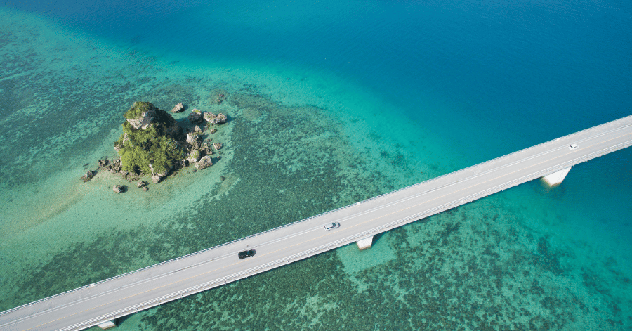 Aerial view of cars crossing a long causeway bridge over turquoise reef shallows