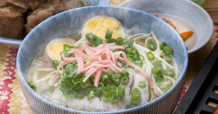 Bowl of Okinawa soba with sliced pork belly, spring onion, pink fish cake and boiled egg