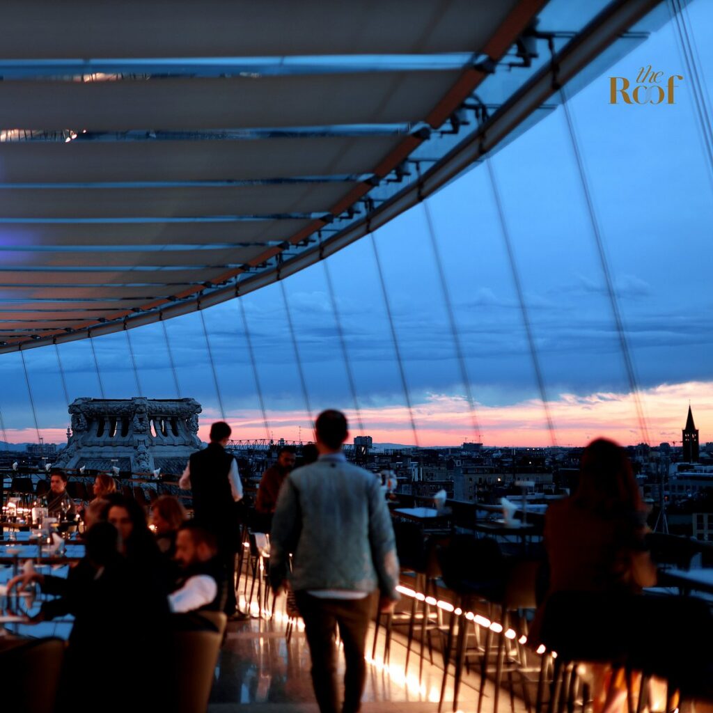 Guests at The Roof Milano rooftop bar at dusk overlooking the Milan skyline