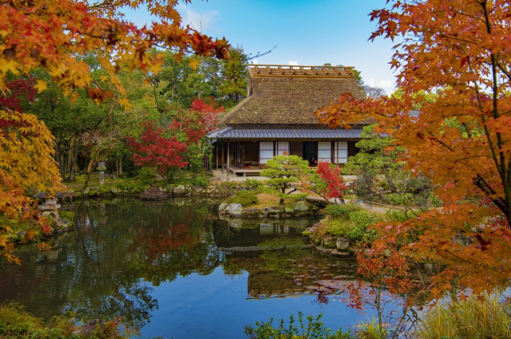 Isuien Garden's pond and traditional teahouse framed by red autumn maple leaves