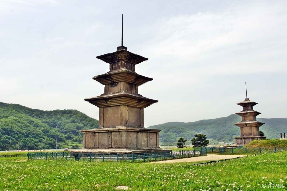 Twin three-storey stone pagodas standing in the grass field of the Gameunsa temple site