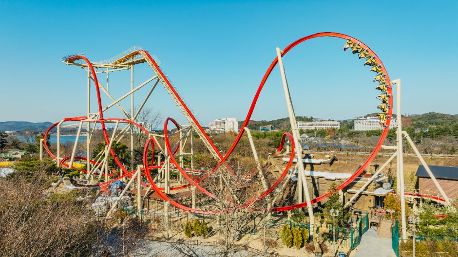 Red looping roller coaster at Gyeongju World with Bomun Lake and resort hotels behind