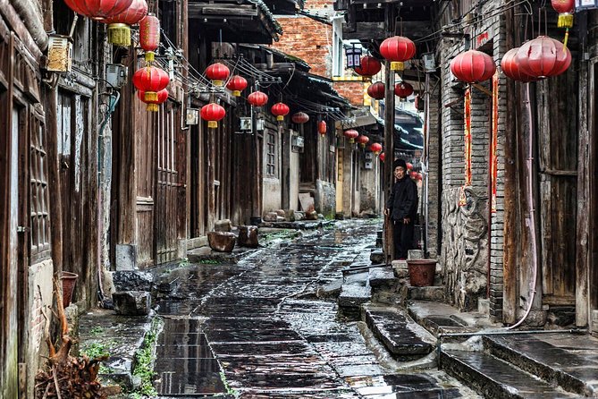 A narrow cobbled alley in Daxu Ancient Town lined with wooden shophouses and red lanterns