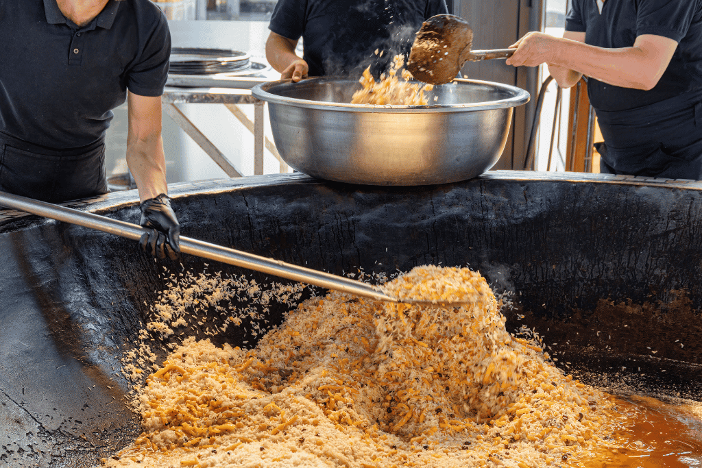 Cooks preparing plov in giant cauldrons at Besh Qozon Plov Centre, Tashkent