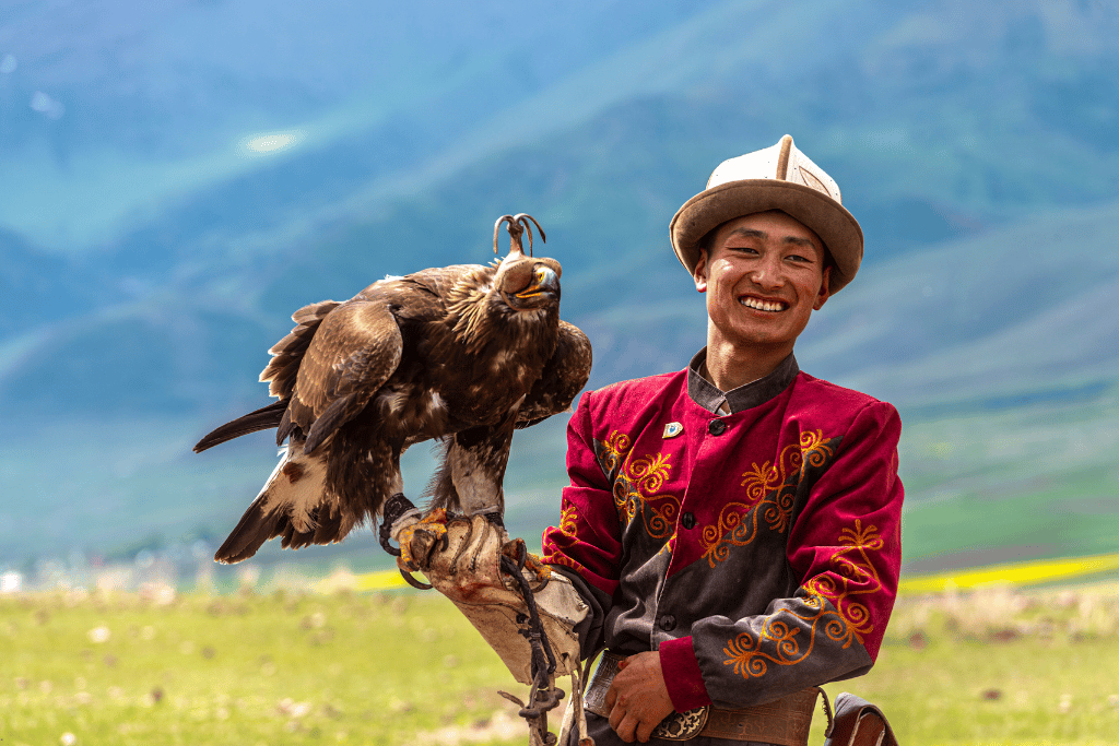 A traditional Kyrgyz eagle hunter on horseback with a golden eagle on his arm