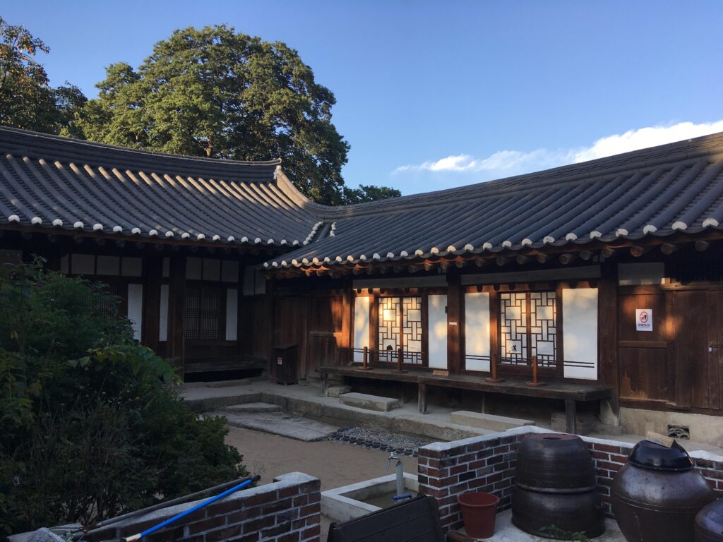 Courtyard of a traditional hanok at Gyochon Village, with lit paper doors and onggi jars