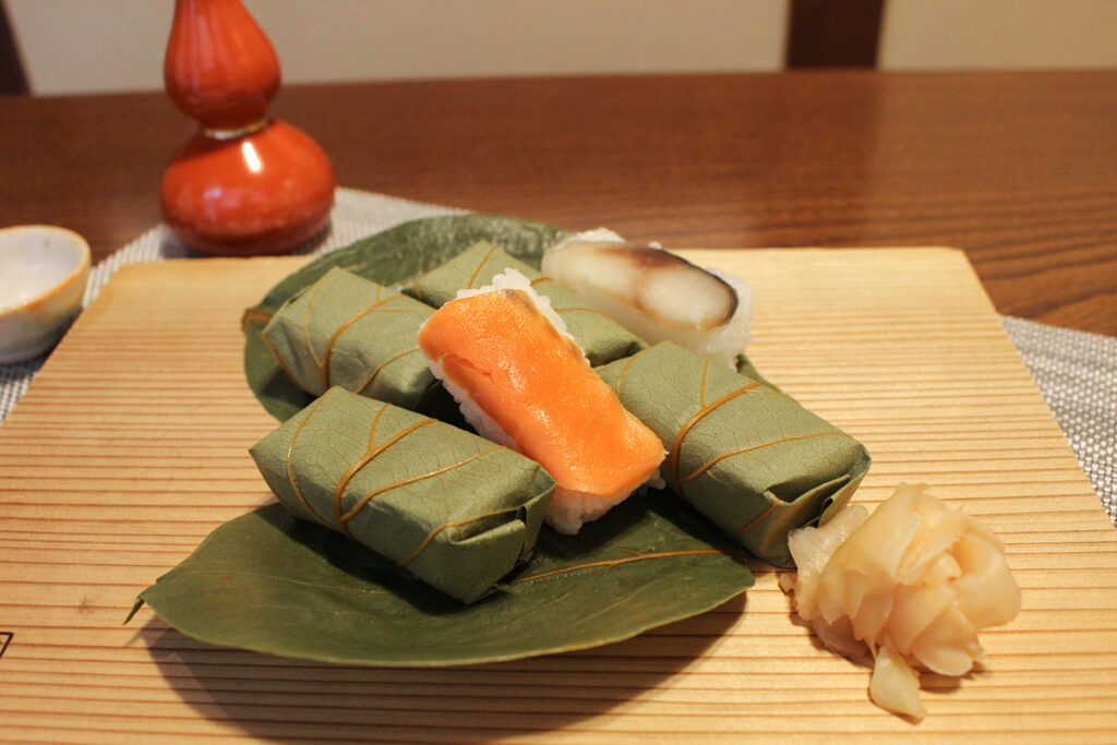 Kakinoha-zushi, salmon and mackerel sushi wrapped in persimmon leaves, served on a plate