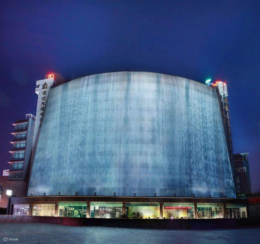 A wall of water cascading down the full front facade of the Lijiang Waterfall Hotel at night