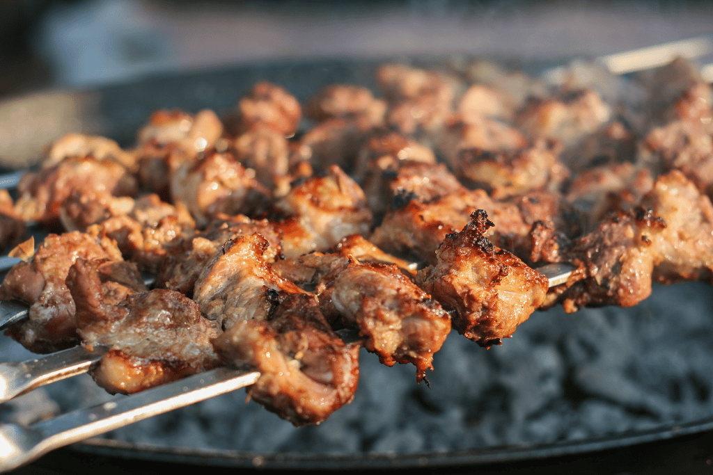 Skewered grilled meat shashlik topped with raw onion at a street-food stall