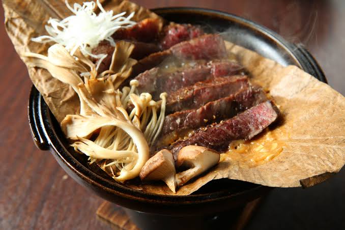 Sliced Kobe beef grilled with mushrooms and served on a hoba leaf
