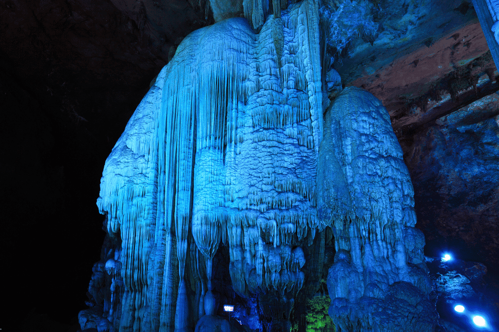 Blue-lit stalactite formations hanging inside Silver Cave