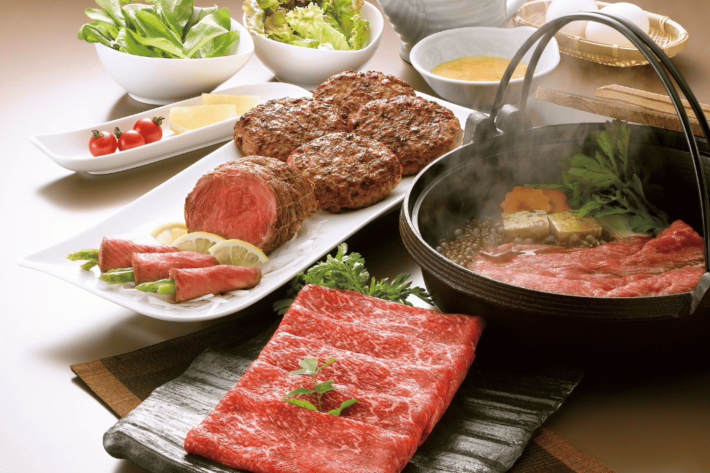 A full Kobe beef course with sukiyaki hot pot, patties, and raw cuts on a table