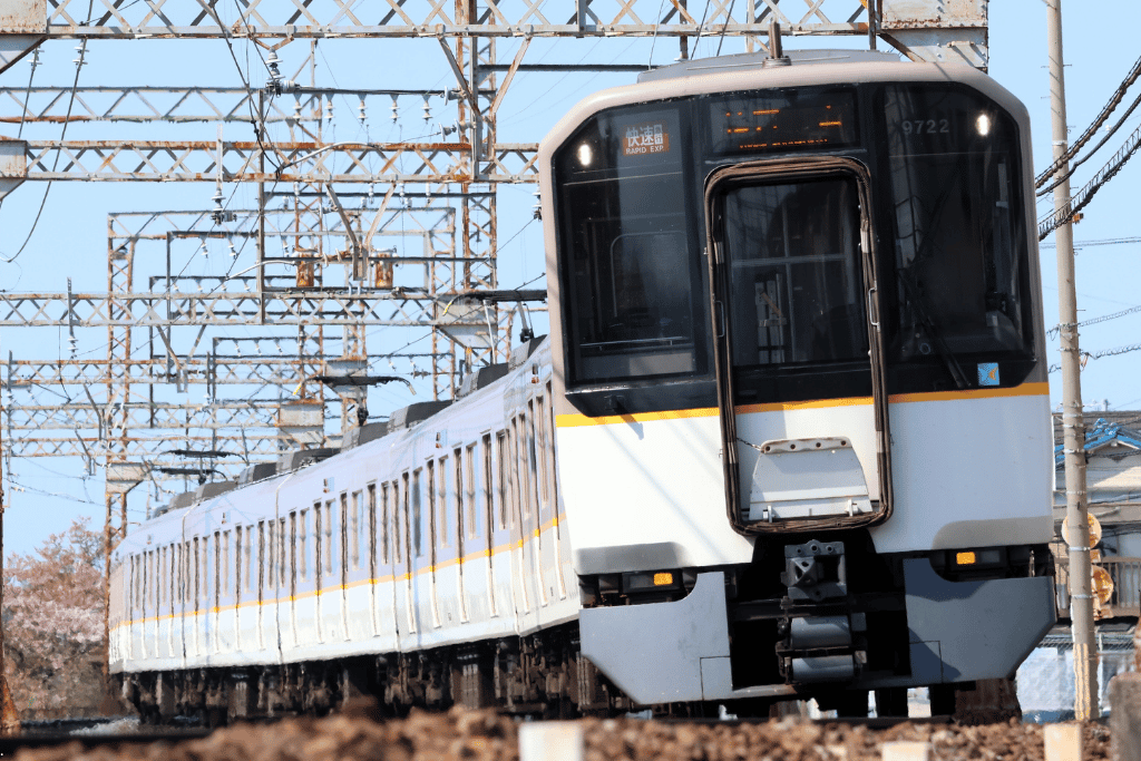 A white and orange Kintetsu limited express train arriving at a station platform