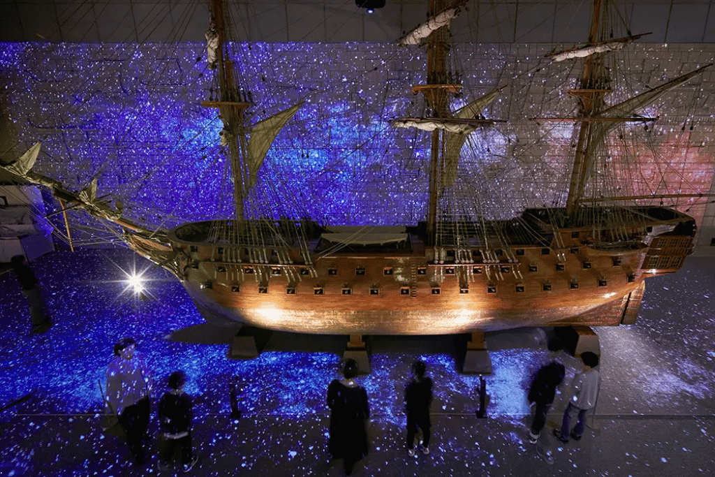 Large historic ship model on display inside the Kobe Maritime Museum with a starfield light show