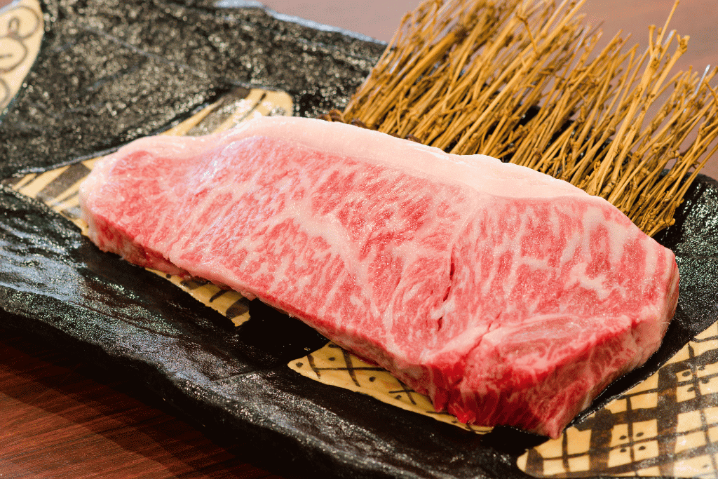 A thick, heavily marbled Kobe beef cut plated on a black serving stone