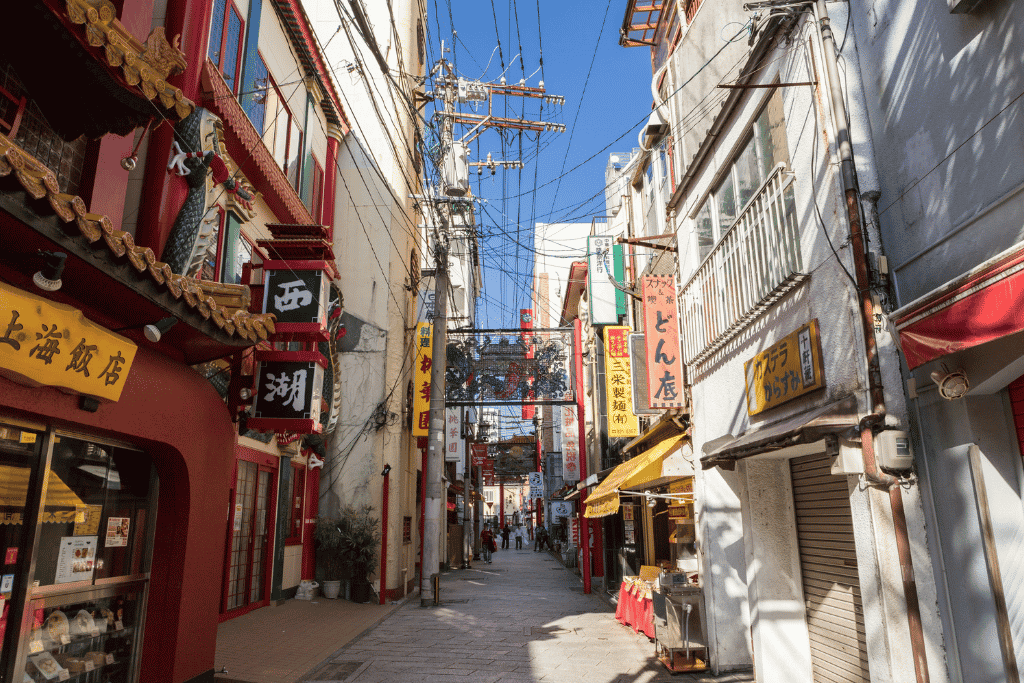 A narrow lantern-lined street in Nagasaki's Shinchi Chinatown lined with restaurant signs