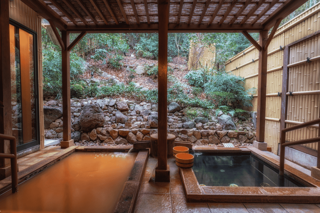 Two outdoor hot-spring baths at Arima Onsen, one rust-brown and one clear