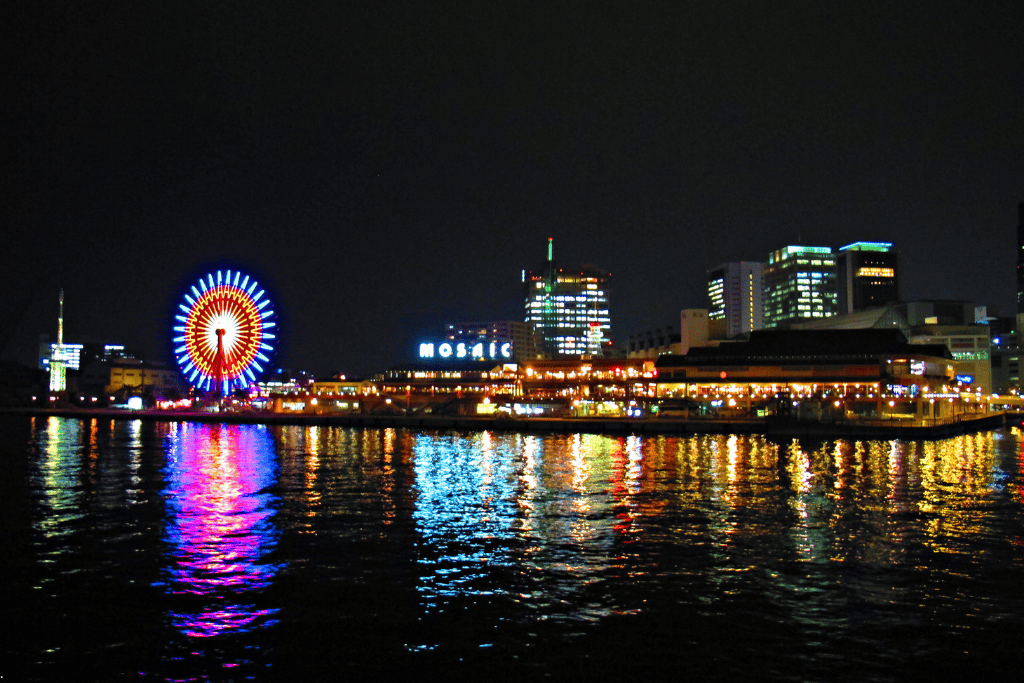 The Mosaic Ferris wheel and Harborland waterfront lit up at night, reflected in the harbour
