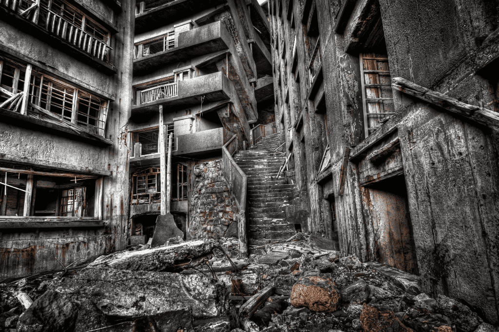 Black and white photo of crumbling stairwells and corridors inside Gunkanjima's abandoned apartment blocks