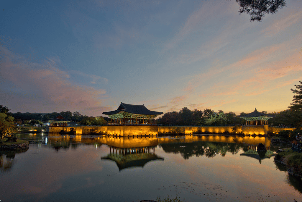 Floodlit pavilions of Donggung Palace reflected in the still water of Wolji Pond at dusk