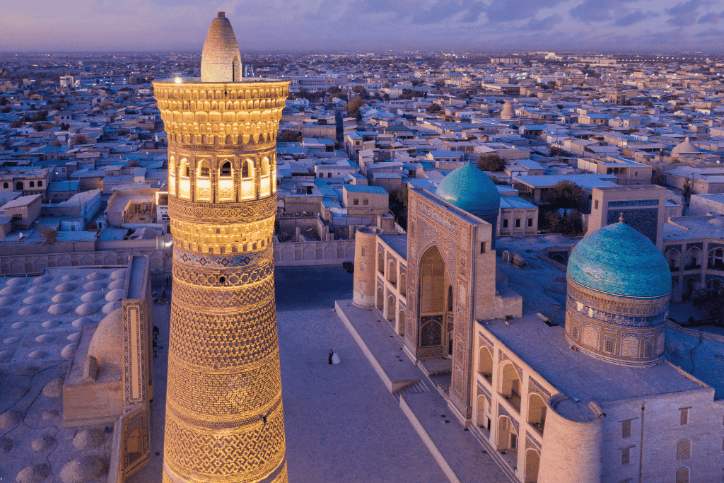 Aerial view of Bukhara's old town at dusk with the lit-up Kalyan Minaret and Poi Kalyan complex