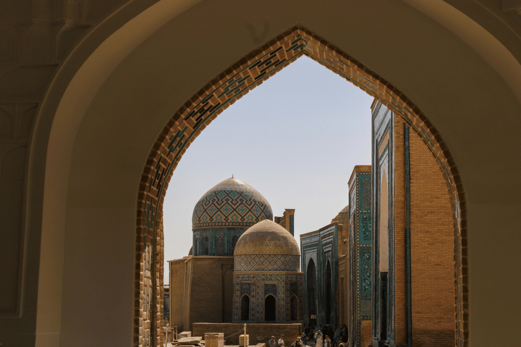 Tiled mausoleum domes in Samarkand framed by a stone archway