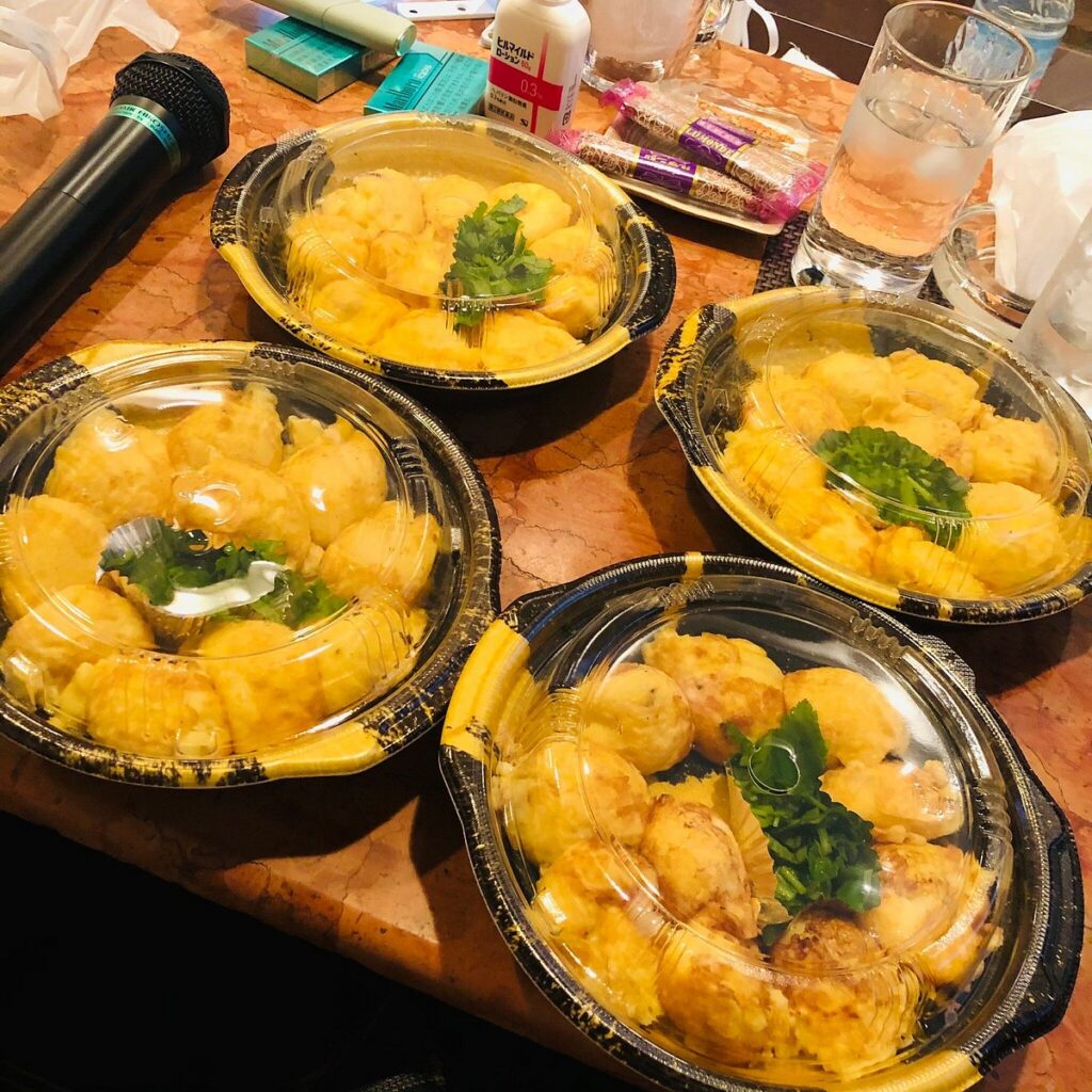 Four plates of pale, egg-battered akashi-yaki balls with garnish