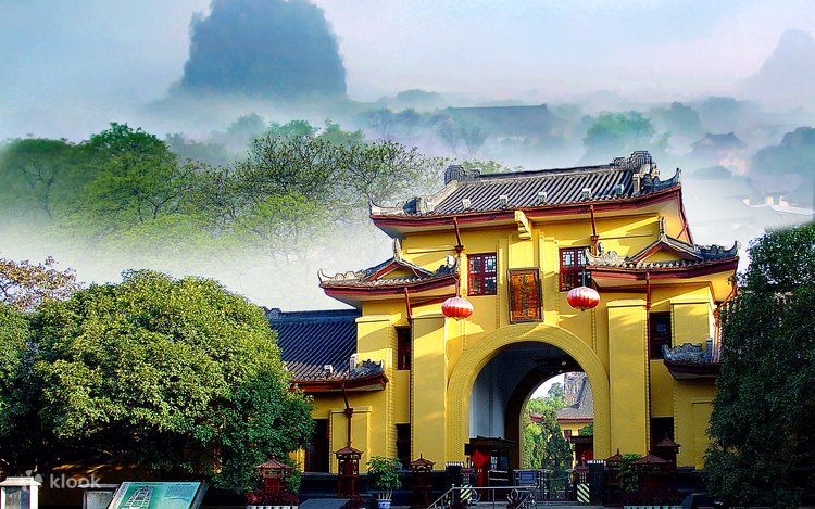 A golden gate tower with red lanterns at the entrance to Jingjiang Princes' City, mist behind