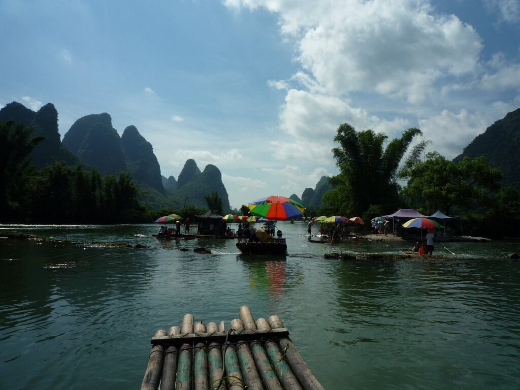 View from a bamboo raft drifting down the Yulong River past colourful umbrella-covered rafts