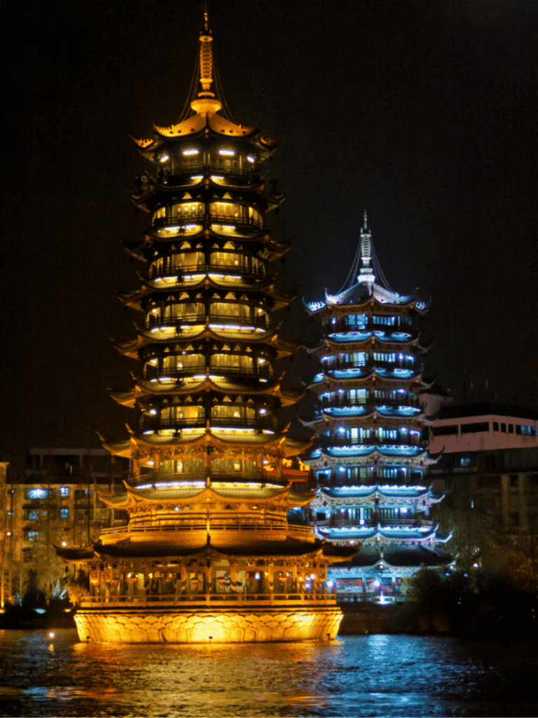The gold Sun Pagoda and silver Moon Pagoda lit up at night on Shan Lake