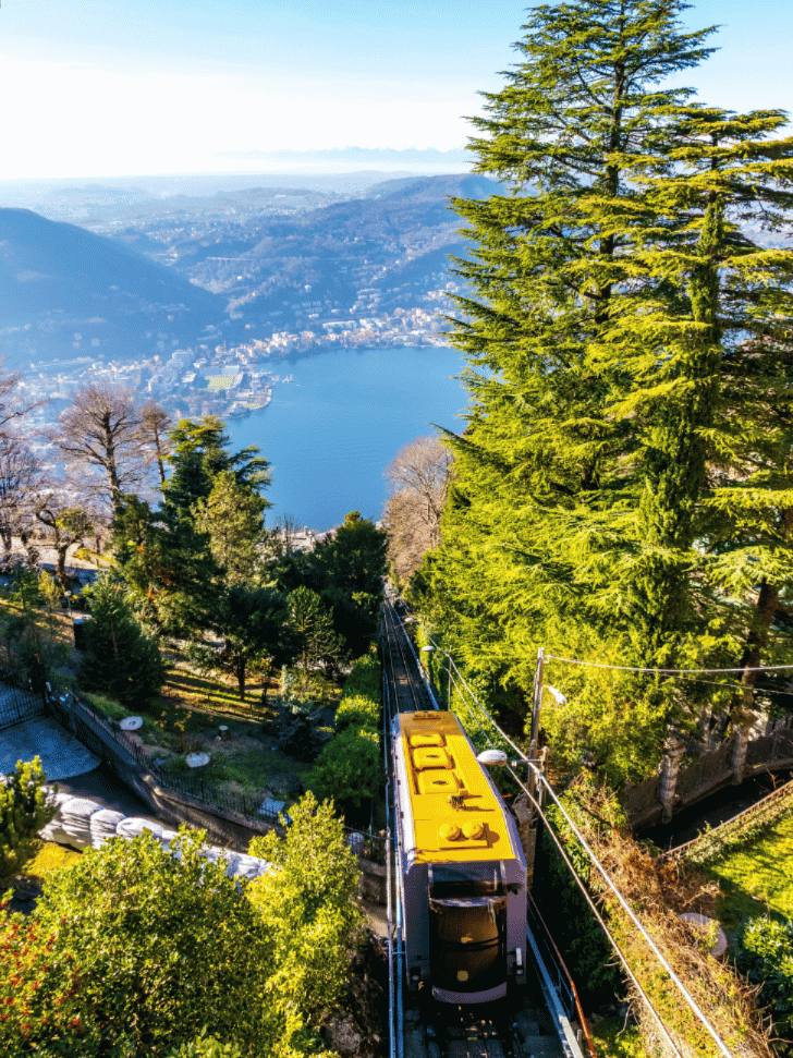 Yellow funicular carriage climbing toward Brunate above Lake Como