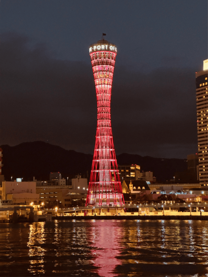 Kobe Port Tower lit red at night, reflected in the harbour water